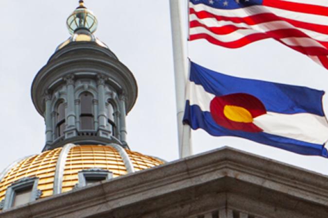 the colorado flag flying above the state capitol