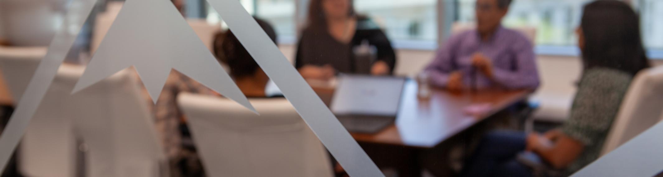 A blurred image of people sitting in a conference room