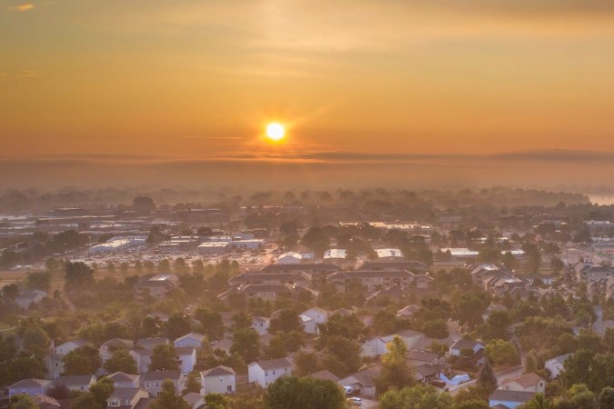 The sun setting over a town on a smoky day