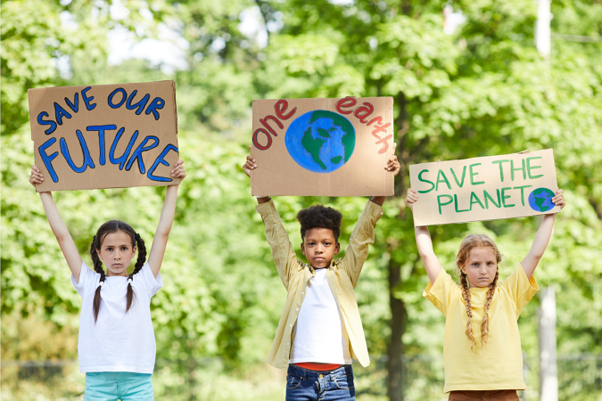 Three children holding homemade signs saying Save Our Future and One Earth