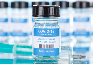 A small, clear bottle with a COVID-19 vaccine label